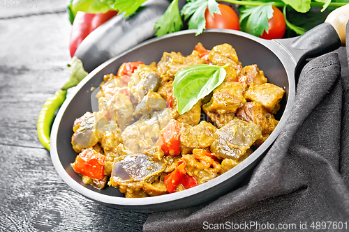 Image of Meat with eggplant and pepper in pan on black board