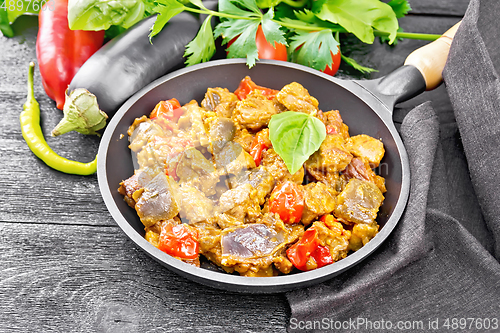 Image of Meat with eggplant and pepper in pan on dark board