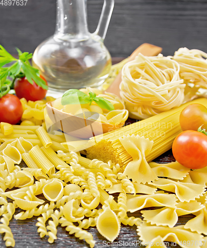 Image of Pasta different with oil and tomatoes on dark board