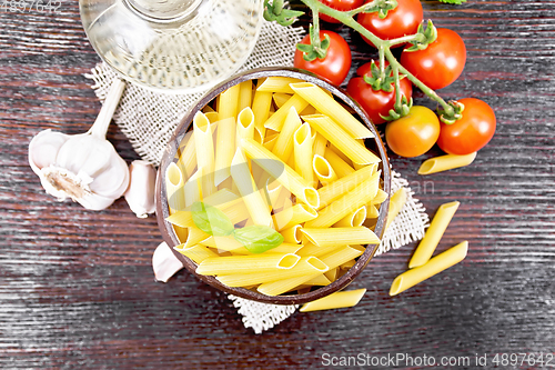 Image of Penne in bowl of coconut with vegetables on dark board top