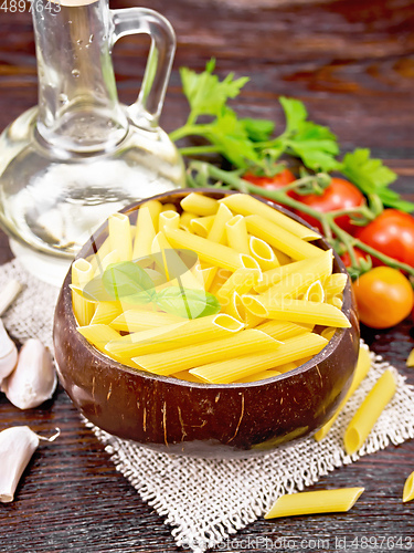 Image of Penne in bowl of coconut with vegetables on dark board