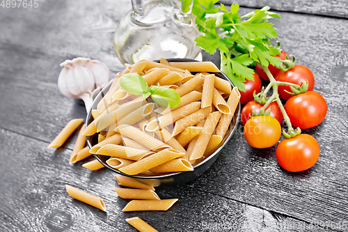 Image of Penne whole grain in bowl with vegetables on black board