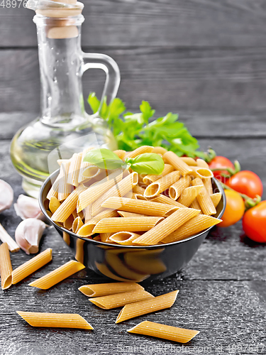 Image of Penne whole grain in bowl with vegetables on dark board