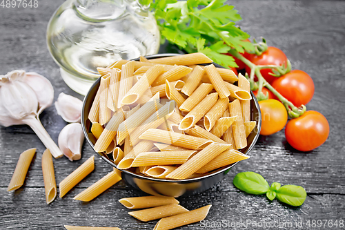 Image of Penne whole grain in bowl with vegetables on wooden board