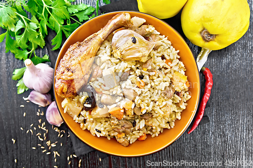 Image of Pilaf with duck and quince in plate on dark board top