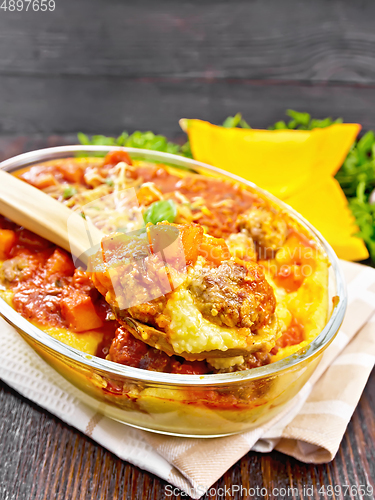 Image of Porridge corn with meat and spoon in roaster on wooden board