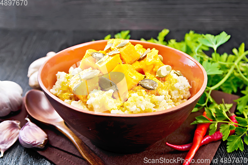 Image of Porridge millet with spicy pumpkin in clay bowl on black board