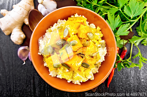 Image of Porridge millet with spicy pumpkin in clay bowl on board top