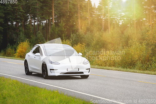 Image of White Tesla Model 3 Electric Car on Rural Highway