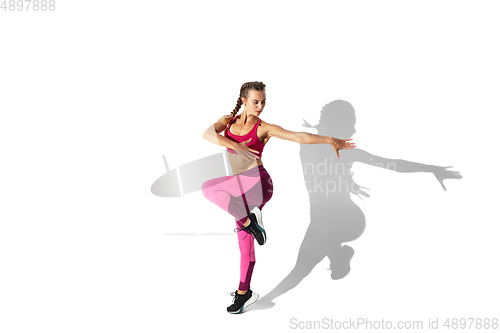 Image of Beautiful young female athlete practicing on white studio background with shadows