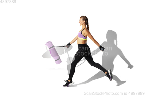 Image of Beautiful young female athlete practicing on white studio background with shadows