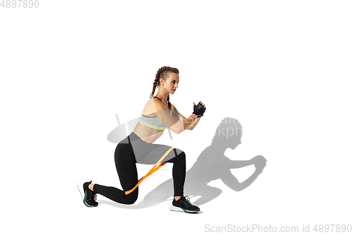 Image of Beautiful young female athlete practicing on white studio background with shadows