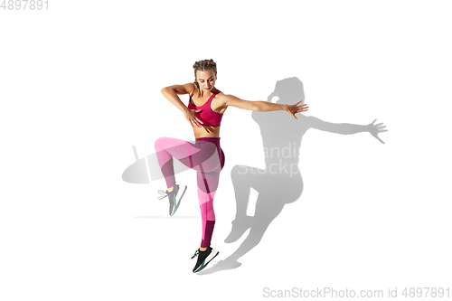 Image of Beautiful young female athlete practicing on white studio background with shadows