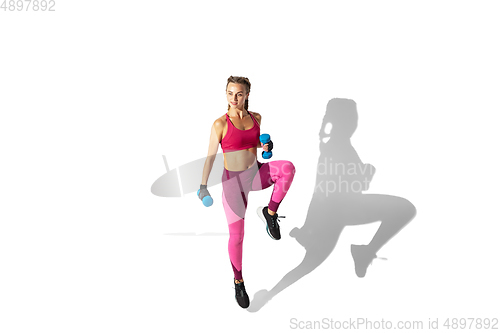 Image of Beautiful young female athlete practicing on white studio background with shadows