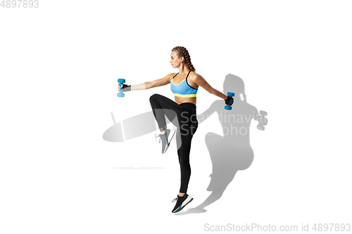 Image of Beautiful young female athlete practicing on white studio background with shadows