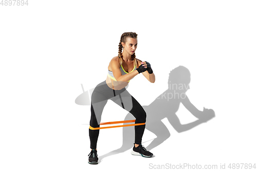 Image of Beautiful young female athlete practicing on white studio background with shadows