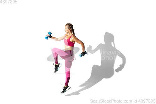 Image of Beautiful young female athlete practicing on white studio background with shadows