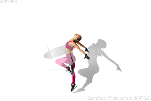 Image of Beautiful young female athlete practicing on white studio background with shadows