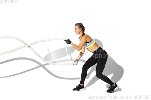 Image of Beautiful young female athlete practicing on white studio background with shadows