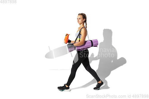 Image of Beautiful young female athlete practicing on white studio background with shadows