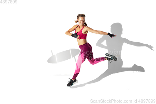 Image of Beautiful young female athlete practicing on white studio background with shadows