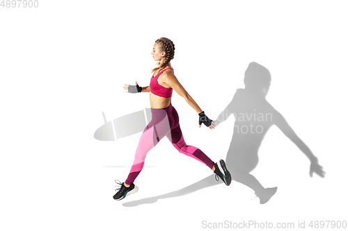 Image of Beautiful young female athlete practicing on white studio background with shadows