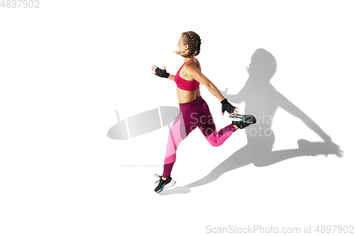 Image of Beautiful young female athlete practicing on white studio background with shadows