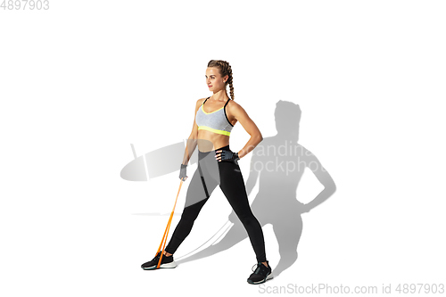 Image of Beautiful young female athlete practicing on white studio background with shadows