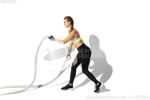 Image of Beautiful young female athlete practicing on white studio background with shadows