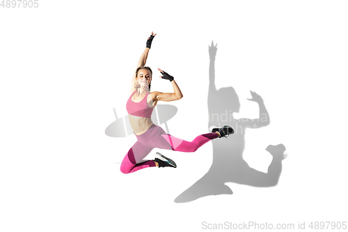 Image of Beautiful young female athlete practicing on white studio background with shadows