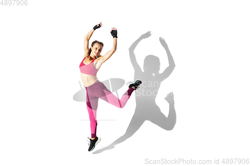 Image of Beautiful young female athlete practicing on white studio background with shadows