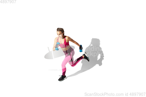 Image of Beautiful young female athlete practicing on white studio background with shadows