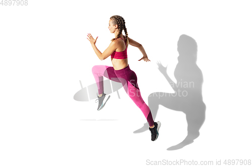 Image of Beautiful young female athlete practicing on white studio background with shadows