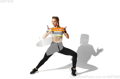 Image of Beautiful young female athlete practicing on white studio background with shadows