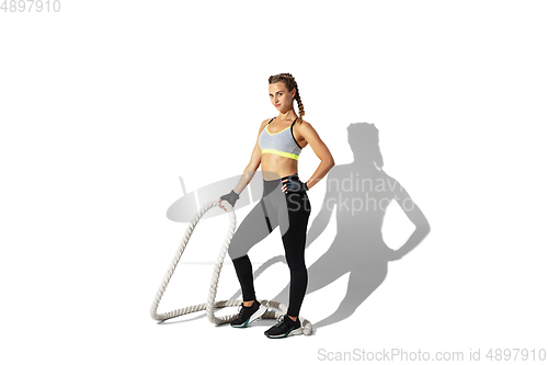 Image of Beautiful young female athlete practicing on white studio background with shadows