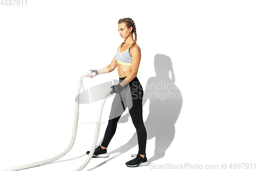 Image of Beautiful young female athlete practicing on white studio background with shadows