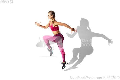 Image of Beautiful young female athlete practicing on white studio background with shadows