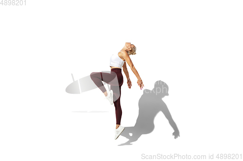 Image of Beautiful young female athlete practicing on white studio background with shadow