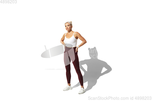 Image of Beautiful young female athlete practicing on white studio background with shadow