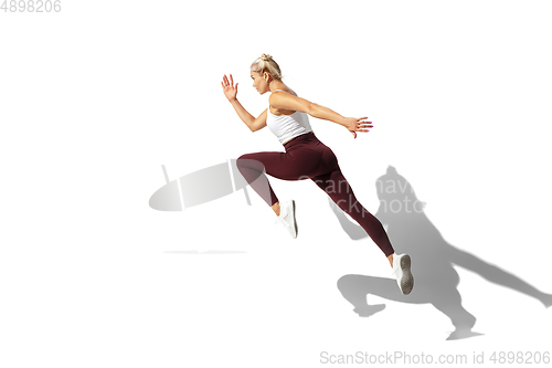 Image of Beautiful young female athlete practicing on white studio background with shadow