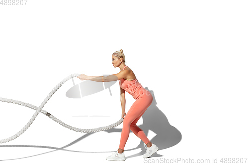 Image of Beautiful young female athlete practicing on white studio background with shadow