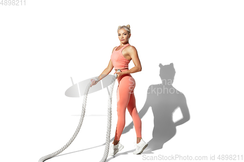 Image of Beautiful young female athlete practicing on white studio background with shadow