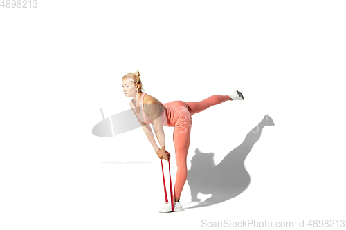 Image of Beautiful young female athlete practicing on white studio background with shadow