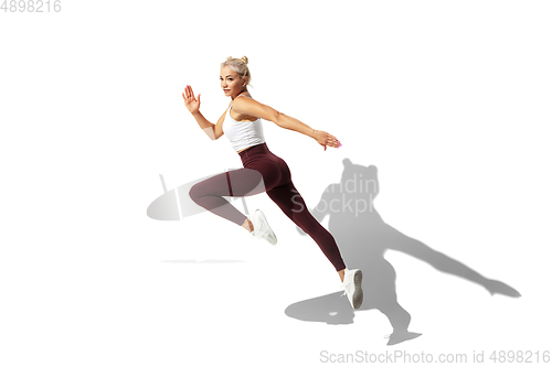 Image of Beautiful young female athlete practicing on white studio background with shadow