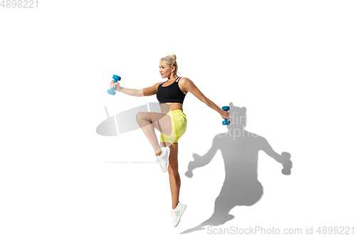 Image of Beautiful young female athlete practicing on white studio background with shadow