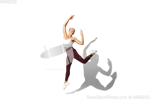 Image of Beautiful young female athlete practicing on white studio background with shadow