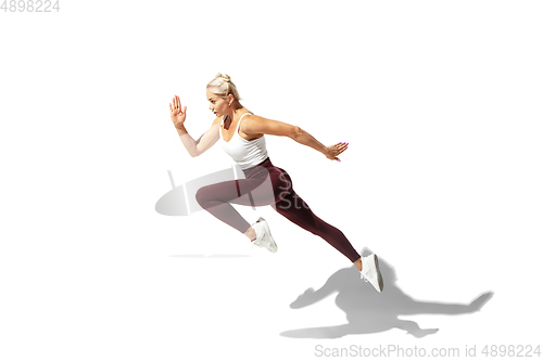 Image of Beautiful young female athlete practicing on white studio background with shadow