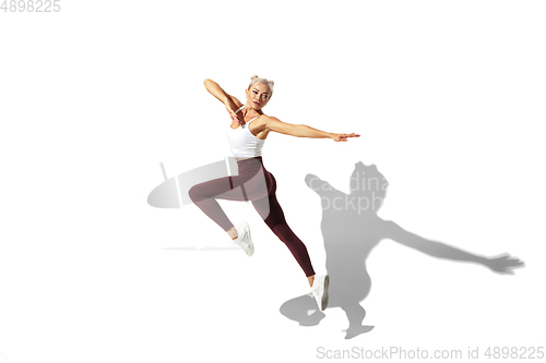 Image of Beautiful young female athlete practicing on white studio background with shadow