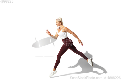 Image of Beautiful young female athlete practicing on white studio background with shadow