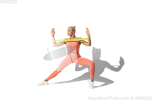 Image of Beautiful young female athlete practicing on white studio background with shadow